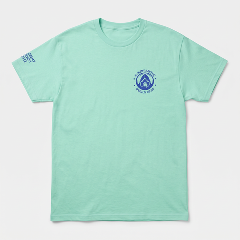 Mint green Alchemy Harvest Coffee cotton t-shirt featuring a front logo print and a distressed back graphic of a cat carrying four cold brew cans.
