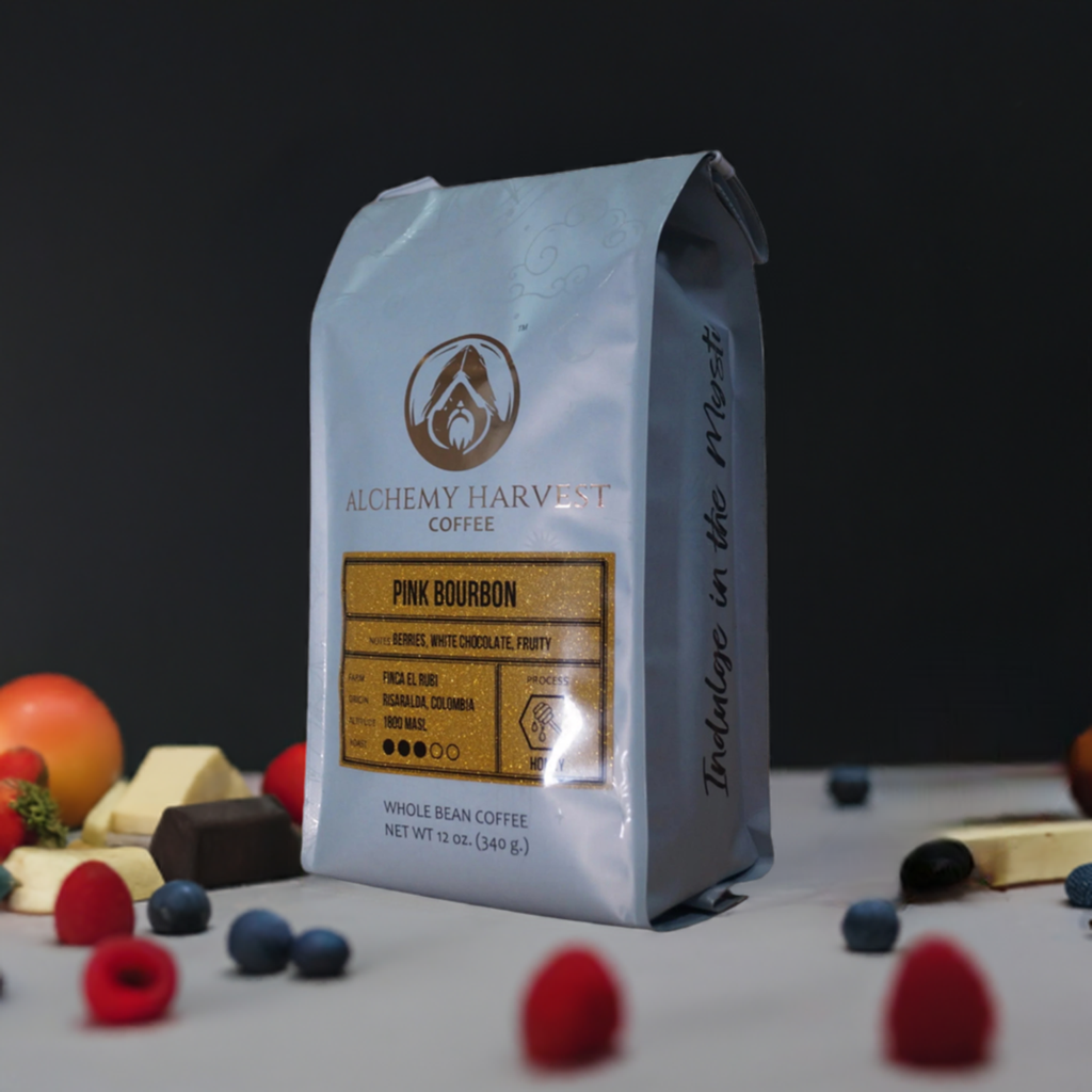 A bag of Alchemy Harvest Coffee's Pink Bourbon honey process coffee beans, surrounded by an assortment of fruits and cheeses on a white surface.